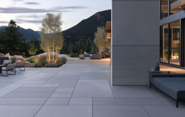 Modern courtyard paved in large-format gray pavers with lounge seating, a fire pit and aspen trees