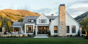Mountain farmhouse with a natural stone chimney and foothills behind it at sunset